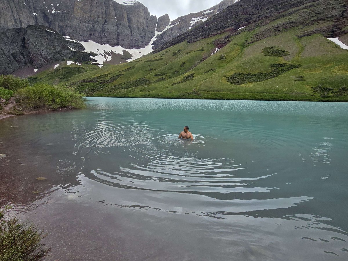 A turquoise glacial lake below a cirque of snow-streaked mountains.