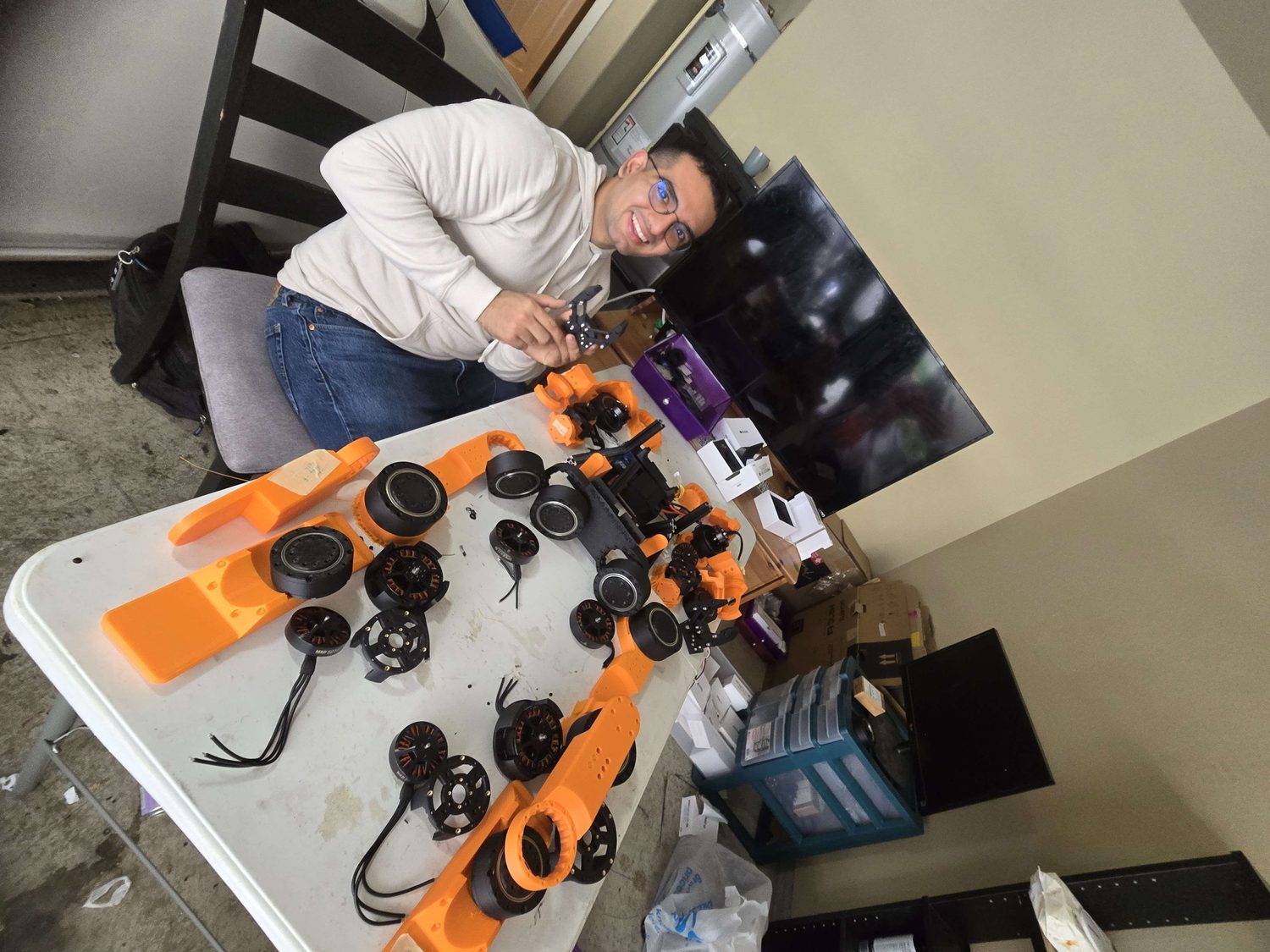 Bins of orange and black 3D-printed structural parts for the humanoid.